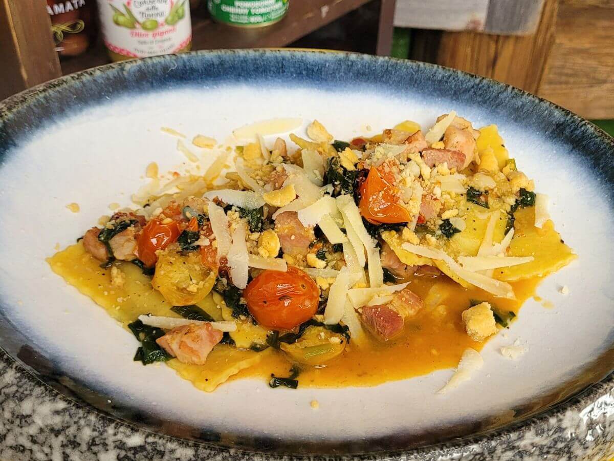 Teller mit gefüllter Bärlauch-Pasta und Pancetta, Kirschtomaten und frischem Bärlauch.